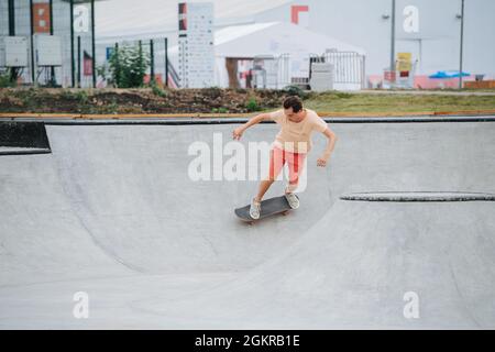 Speedy Mann Skater in bunten Kleidern Reiten auf ihrem Brett auf Viertel Rohr Kreis Stockfoto