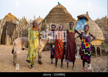 Frauen mit einem Esel vor ihrer Hütte, Jiye-Stamm, Eastern Equatoria State, Südsudan, Afrika Stockfoto
