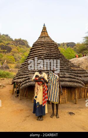 Traditionell gekleidete junge Mädchen aus dem Stamm der Laarim vor ihrer Hütte, Boya Hills, Eastern Equatoria, Südsudan, Afrika Stockfoto