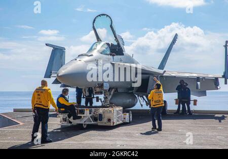 210619-N-NY362-1024 ANDAMANISCHE SEE (19. Juni 2021) Matrosen bereiten sich darauf vor, eine F/A-18E Super Hornet, die an das Eagles of Strike Fighter Squadron (VFA) 115 angeschlossen ist, in die Hangarbucht des einzigen vorwärts eingesetzten Flugzeugträgers der US Navy USS Ronald Reagan (CVN 76) zu bringen. Ronald Reagan, das Flaggschiff der Carrier Strike Group 5, stellt eine kampfbereite Truppe bereit, die die Vereinigten Staaten sowie die kollektiven maritimen Interessen ihrer Verbündeten und Partner in der Indo-Pazifik-Region schützt und verteidigt. Stockfoto