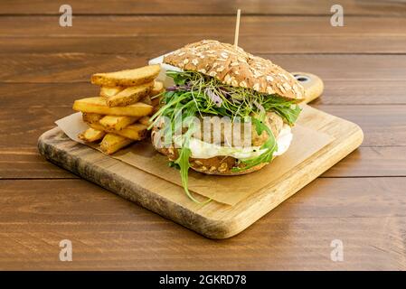 Knuspriger Chicken Burger mit Mayonnaise, Arugula und Bohnensprossen mit Seed Bread und Pommes Frites Stockfoto