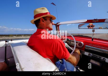 Mann im Strohhut fährt Oldtimer entlang der Malecon, Havanna, Kuba, Westindien, Mittelamerika Stockfoto