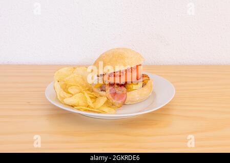 Beef Burger mit geräuchertem Speck, geschmolzenem Cheddar-Käse, Tomatenscheiben, Landbrot und Pommes Stockfoto