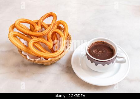 Beliebtes spanisches Frühstück oder ein Schokoladensnack mit Churros im Madrider Stil auf einem weißen Marmortisch Stockfoto