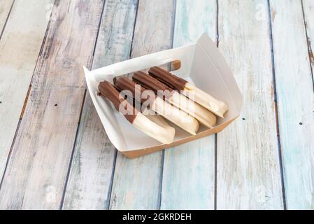 Churros-Ration mit zwei Pralinen auf einem Hausliefercontainer Stockfoto