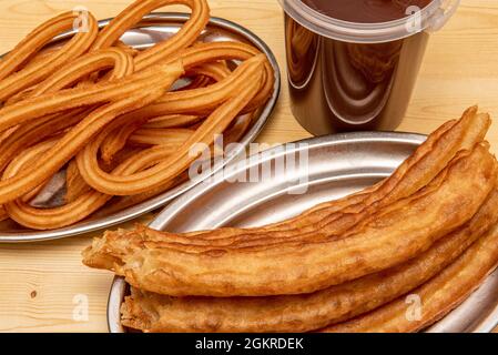 Churros und porras im Madrider Stil auf Metalltabletts und heißer Schokolade Stockfoto