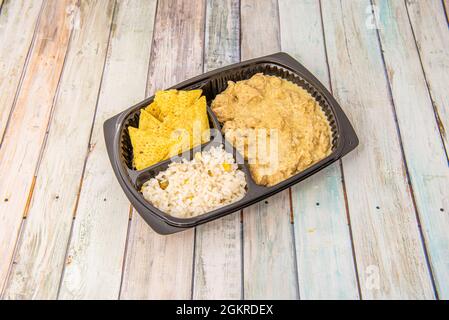 Mexikanische Speisekarte mit Kürbisblüten-Hühnereintopf mit Tortilla-Chips und weißem Reis mit gelbem Mais auf dem Tablett zum Mitnehmen Stockfoto