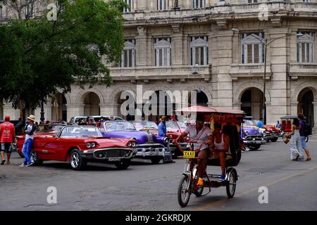 Eine Fahrradkutsche fährt vorbei an vielen klassischen Oldtimern, Havanna, Kuba, Westindien, Mittelamerika Stockfoto