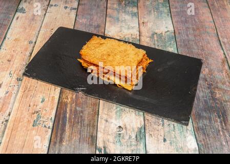 Italienisches Rezept für Fleischlasagne mit Scheiben Pasta und Tomaten auf schwarzem Schieferteller Stockfoto