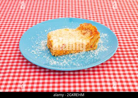 Hähnchenlasagne mit Nudelschichten mit Bechamelgratin und geriebenem Käse auf einem blauen Teller Stockfoto