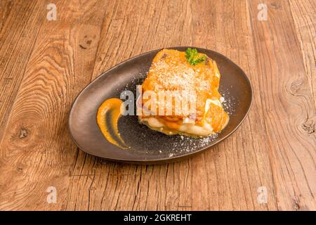 Typisch italienisches Rezept für Kürbislasagne, Provolone-Käse und geriebenen Käse auf schwarzem Teller Stockfoto