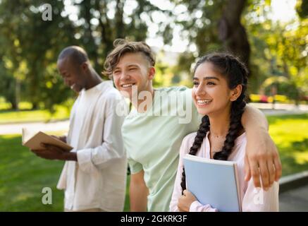 Freizeit der Studenten. Glückliche, vielfältige Universitätsfreunde, die auf dem Campus zusammenlaufen, im Freien plaudern und lachen Stockfoto