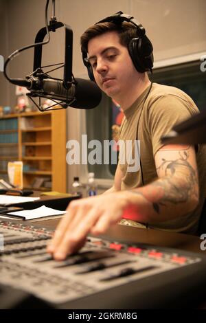 Personal Sgt. Samuel Burns, ein Rundfunkjournalist vom American Forces Network-Tokyo, passt die Mikrofonlautstärke an, während er „Shogo Radio“ vom Flugplatz Yokota, Japan, am 23. Juni 2021 hostet. „Shogo Radio“ ist eine regionale Radiosendung, die in ganz Japan ausgestrahlt wird und strategische INDOPACOM-Botschaften sowie Unterhaltung für Servicemitglieder und ihre Familien unterstützt. Stockfoto