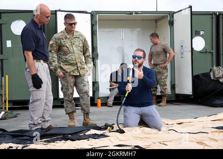 GEMEINSAME BASIS LANGLEY-EUSTIS, VA. (22. Juni 2021) John Foden und US Army Sgt. 1st Class Gary Cato, dem Joint Task Force Logistics Directorate zugewiesen, hört zu, wie Kyle Rinehart, Logistik- und Service-Spezialist bei HDT Global, zeigt, wie der Luftdruck für das Luftzelt in Vorbereitung auf die Übung Lightning Response überprüft werden kann. Die Übung besteht aus einem gemeinsamen Operations Center und einer Übung zur Einsatzbereitschaft, um sicherzustellen, dass der Befehl in der Lage ist, mehrere Support-Teams für Vorfälle zur Unterstützung eines CBRN- oder aller Gefahren-DSCA-Ereignisses einzusetzen. Die Übung bestätigt auch neue Standard-Betrieb verübt Stockfoto