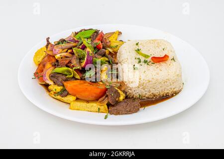 Tablett mit Rinderfilet mit Paprika, Tomaten, Zwiebeln, Schnittlauch und Petersilie, zubereitet mit peruanischem Rezept mit weißem Reis, pommes frites und Vegetabl Stockfoto