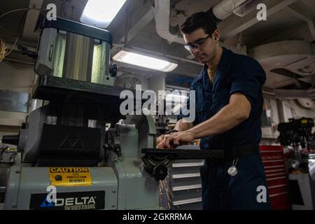 210623-N-XR893-0026 ATLANTISCHER OZEAN (23. Juni 2021) Flugzeugbaumechaniker-Auszubildender Grayson Montgomery aus Tallahassee, Florida, schneidet im Jet-Shop an Bord des Flugzeugträgers USS Harry S. Truman in der Nimitz-Klasse mit einem Bandschleifer ein Blech (CVN 75) Während der TSTA (Tailored Ship’s Training Availability) und FEP (Final Evaluation Problem). Harry S. Truman, mit dem eingeschifften Carrier Air Wing 1, führt derzeit TSTA und FEP durch, um ihre Fähigkeit zur Durchführung von Kampfeinsätzen, zur Unterstützung von Funktionen und zur Überlebensfähigkeit komplexer Unfallkontrollsituationen im Hinblick auf die vollständige Integration zu beurteilen Stockfoto