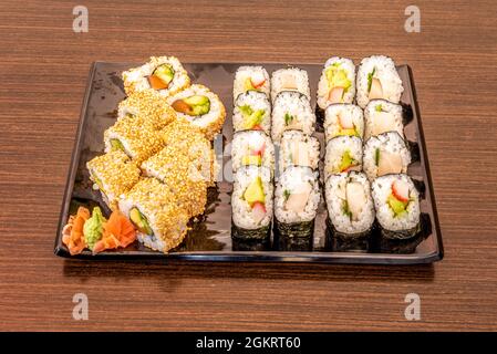 Gemischtes Sushi-Tablett mit Uramaki-Drachenrolle, gefüllt mit Avocado, norwegischem Lachs und Nori-Algen. Maki gefüllt mit Butterfisch, japanischem Reis, sur Stockfoto