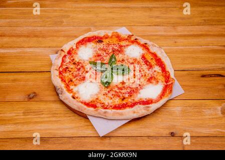 Kleine margarita Pizza mit geschmolzenen Büffelkäsebällchen, Tomaten und Mozzarella-Käse auf weißem, fettfestem Papier Stockfoto
