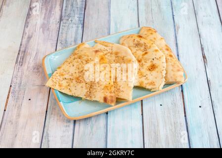 Indischer Naan-Käse in Scheiben geschnittenes Brot mit Sesam auf hellblauer Platte Stockfoto