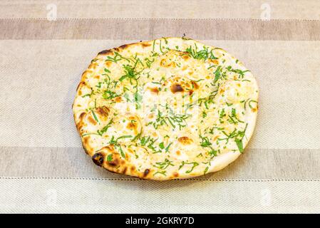 Knoblauch-Naan-Brot mit geriebener Petersilie und Mandelstücken auf grauem Tisch Stockfoto