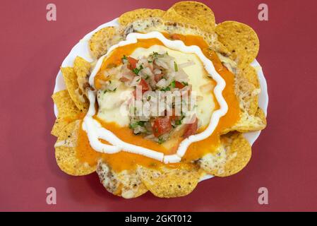 Nachos mit Gratin-Käse, serviert im lateinischen Restaurant auf rotem Tisch Stockfoto