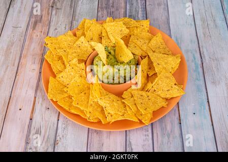 Einfacher Teller mit Mais-Nachos mit mexikanischer Guacamole auf einem Holztisch Stockfoto