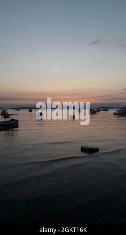 Das Meer und die untergehende Sonne hinter den Booten Stockfoto