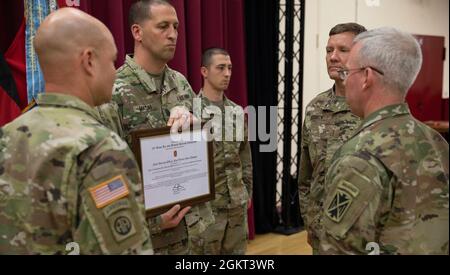 Befehl Sgt. Maj. Giancarlo Macri, Kommandofeldwebel-Major des 10. Armee-Luft- und Raketenabwehrkommandos, bereitet sich darauf vor, die Charta der 10. AAMDC an den Chief Warrant Officer 5 Anson Seebeck, ausscheidender Kommandoführer des 10. AAMDC, Brig, zu übergeben. General Gregory J. Brady, kommandierender General der 10. AAMDC, und Chief Warrant Officer 4 Wesley „Mark“ Dohogn, ankommender Chief Warrant Officer der 10. AAMDC bei einer Charterwechselzeremonie am 24. Juni 2021. Stockfoto