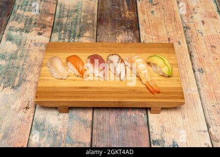 Bambusablage mit verschiedenen Nigiri. Butterfisch Nigiri, norwegischer Lachs, Blauflossen-Thunfisch, geschmorter Eel, gekochte Garnelen und reifer Avocado Stockfoto