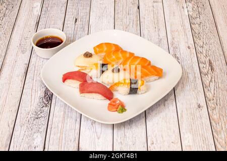 Teller mit gemischtem Lachs-Nigiri-Sushi, Garnelen auf Reis, rotem Thunfisch, Butterfisch mit Fischrogen mit Wasabi und Ginseng mit Schüssel mit Sojasauce Stockfoto