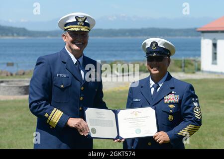 Konteradmiral Anthony 'Jack' Vogt, Kommandant des 13. Bezirks, überreicht dem Kommandomeister des 13. Bezirks, Jason Wong, die Verdienstmedaille während einer Wachwechsel-Zeremonie am Alki Lighthouse in der Nähe von Seattle, Washington, 25. Juni 2021. Master Chief Wong erhielt die Auszeichnung für seine umfangreiche Arbeit zur Förderung von Resilienz und geistiger Gesundheit und Wohlbefinden. Stockfoto