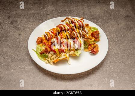 Teller mit kolumbianischen patacón mit vielen Saucen, gebratenen Torreznos, zerfetztem Hühnerfleisch und reifer Kochbanane mit Salat Stockfoto