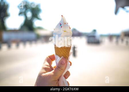 Eiskonus schmilzt und fließt an einem heißen Tag draußen in der Hand. Nahaufnahme, kein Gesicht Stockfoto