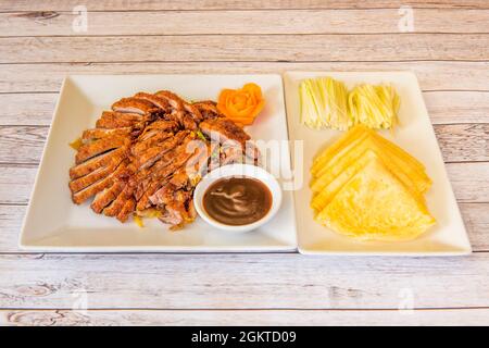 Tabletts mit Pekings-Ente mit Tortillas, Schnittlauch und gebratener Ente mit Sauce, die in einem chinesischen Restaurant für die Lieferung nach Hause gekocht wird Stockfoto