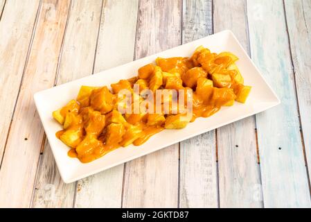 Ration von Patatas Bravas serviert als Tapas in einem Restaurant in Madrid auf einem Holztisch Stockfoto