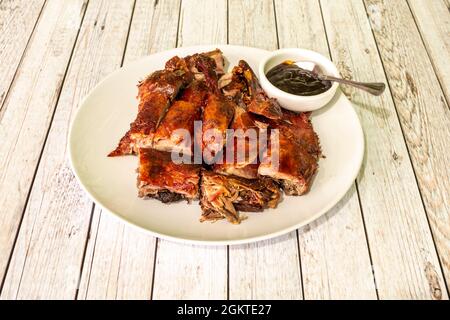 Ganze geröstete Ente im kantonesischen Stil, die bequem zu essen ist, mit typischer Sauce auf einem weißen Teller Stockfoto