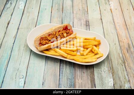 Spezieller Hot Dog mit Senf, Ketchup und knuspriger Zwiebel, garniert mit Pommes Frites in Olivenöl Stockfoto