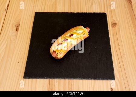 Klassischer Hot Dog mit Mayonnaise, Senf und Ketchup mit geriebenem Käse und gekochter Wurst Stockfoto