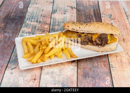 Tolles Sandwich mit geschmortem Fleisch und Pilzen und reichlich geschmolzenem Cheddar-Käse mit einer Seite Pommes Frites Stockfoto