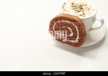 Schokoladen-Biskuitrolle mit Vanillegeschmack und frischem Kaffee in der Tasse, Schweizer Schokoladenrolle, süßer Morgen Stockfoto