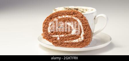 Schokoladen-Biskuitrolle mit Vanillegeschmack und frischem Kaffee in der Tasse, Schweizer Schokoladenrolle, süßer Morgen Stockfoto
