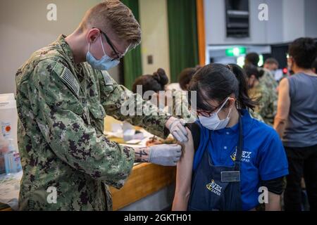 Hospital Corpsman 3rd Class Duncan O’Donnell, der US Naval Hospital Yokosuka Branch Health Clinic Sasebo zugewiesen wurde, bereitet die Impfung von Kaoru Nagamatsu, einem Mitarbeiter bei Commander, Fleet Activities Sasebo’s (CFAS) Navy Exchange, mit dem Impfstoff Moderna COVID-19 während der Impfstoffverteilung im CFAS Showboat Theatre vor 30. Juni 2021. Mit der Genehmigung der Regierung von Japan begann CFAS im Juni 23 mit der Verabreichung von Impfstoffen an MLC-, IHA- und MC-Mitarbeiter. Stockfoto