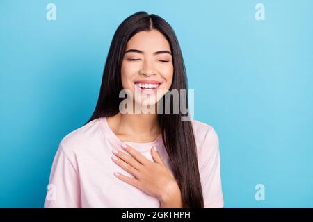 Foto von jungen Mädchen glücklich positive Lächeln Hand auf Brust lachen lustig Witz isoliert über blauen Hintergrund Stockfoto