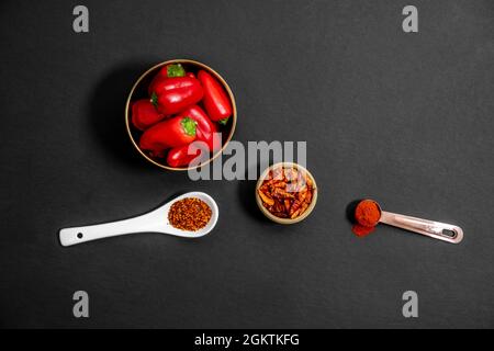 Draufsicht auf goldene Schüssel mit roten Paprika, Cayenne in kleinem Behälter und Paprika in Löffeln Stockfoto