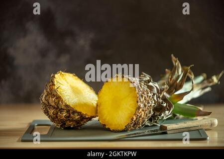 Reife Ananas mit einem Küchenmesser mit Holzschuppen halbieren Stockfoto