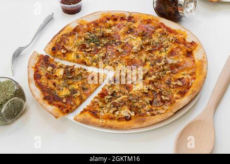 Kleine Pizza mit Tomaten, gebratenen geräucherten Speck und gehackten Walnüssen mit Tomaten und Mozzarella-Käse auf weißem Teller Stockfoto