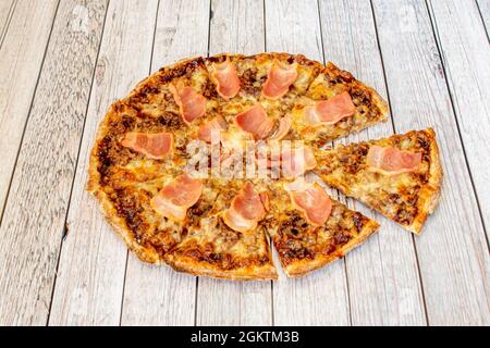 Kleine feine Weizteig-Pizza mit BBQ-Sauce mit riesigen gebratenen Speck-Scheiben und Hackfleisch Stockfoto