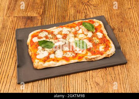 Margarita Pizza mit Büffelmozzarella-Käse im rechteckigen Format mit Basilikum und Tomaten und Weizenmehlteig Stockfoto