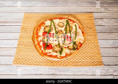 Italienische Pizza mit Kumato-Tomate, gerösteten Paprika, in Scheiben geschnittenen Pilzen und Pesto-Sauce, Mozzarella-Käse Stockfoto