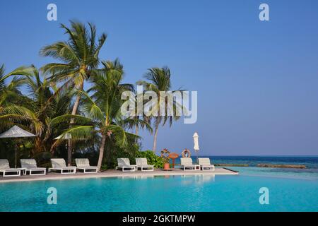 Wunderschönes Resort mit Pool, Lounge Chair, Palm und Meerblick auf den Malediven. Luxuriöser Urlaub auf der maledivischen Insel während des Sommertages. Stockfoto